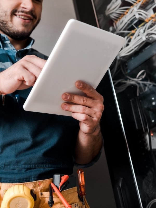 cropped view of happy bearded technician using digital tablet